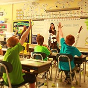 elementary students raising their hands in a classroom
